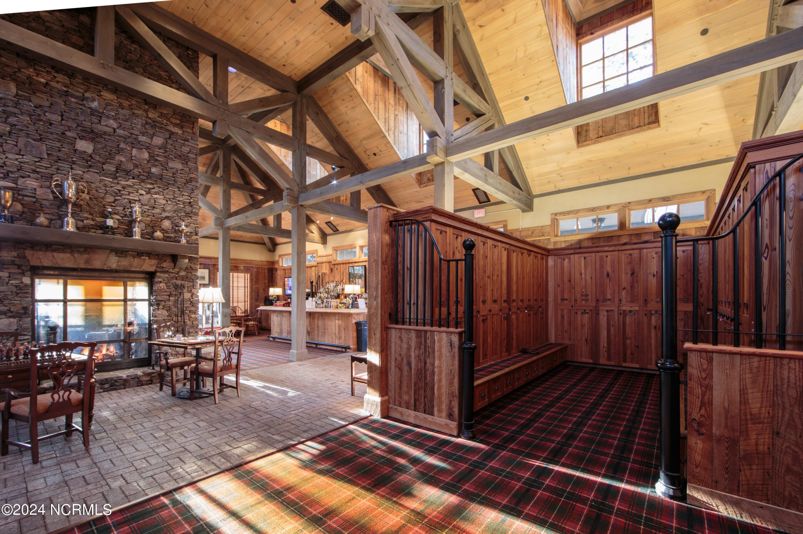 Forest Creek Golf Club clubhouse interior with exposed beams, stone fireplace, and wood lockers in Pinehurst, NC.