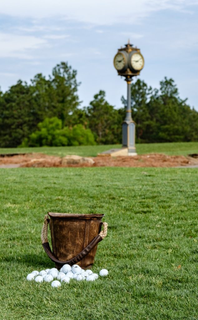 Leather bucket of golf balls on the Forest Creek Golf Club driving range with signature clock tower in Pinehurst, NC.